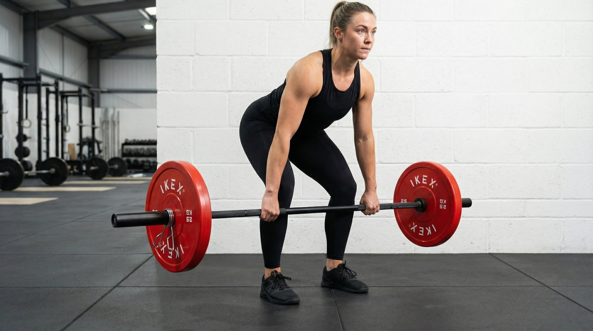 Atleta entrenando con discos técnicos rojos IKEX de 2,5 kg en barra olímpica